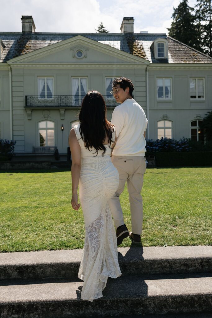 Couple walking up the stairs at Bloedel Reserve with The Residence in the background.