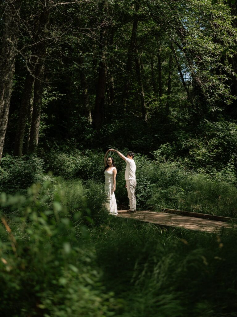 Man twirling his fiance for their outdoor engagement photos at Bloedel Reserve.