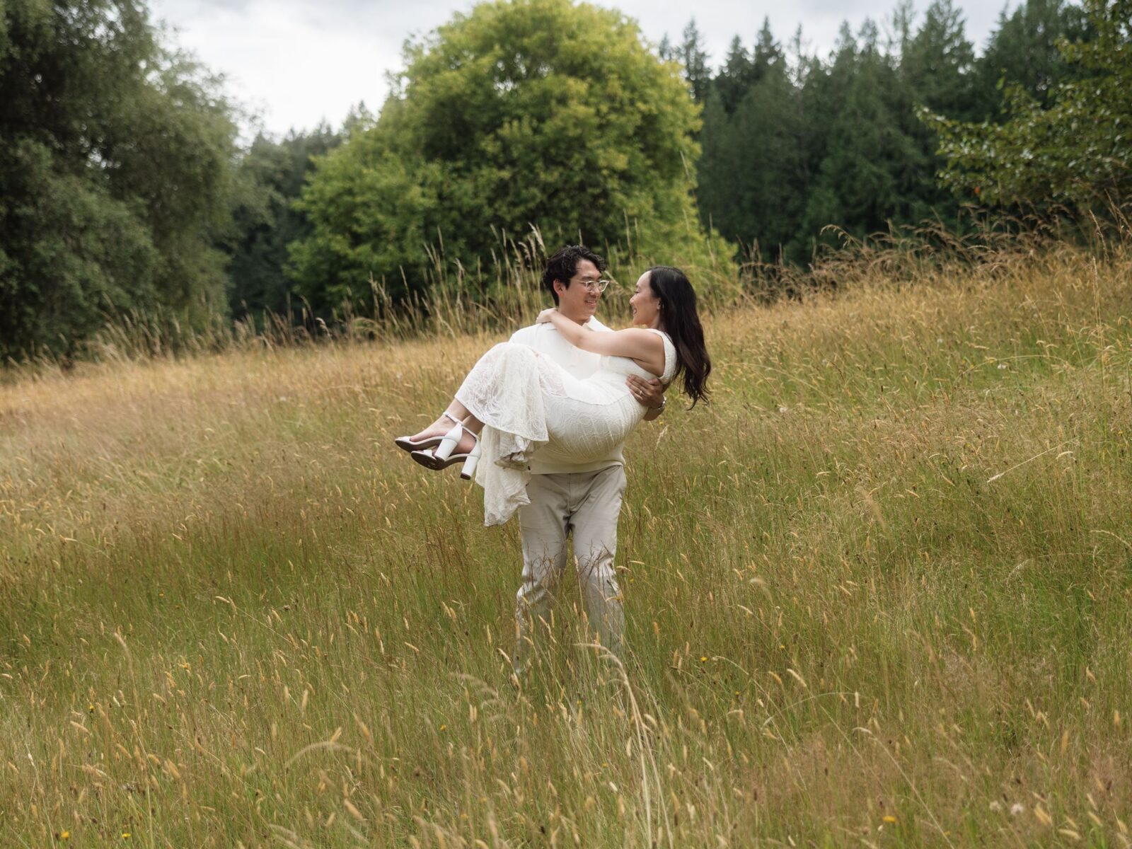 Man holding his fiancé in his arms in field.