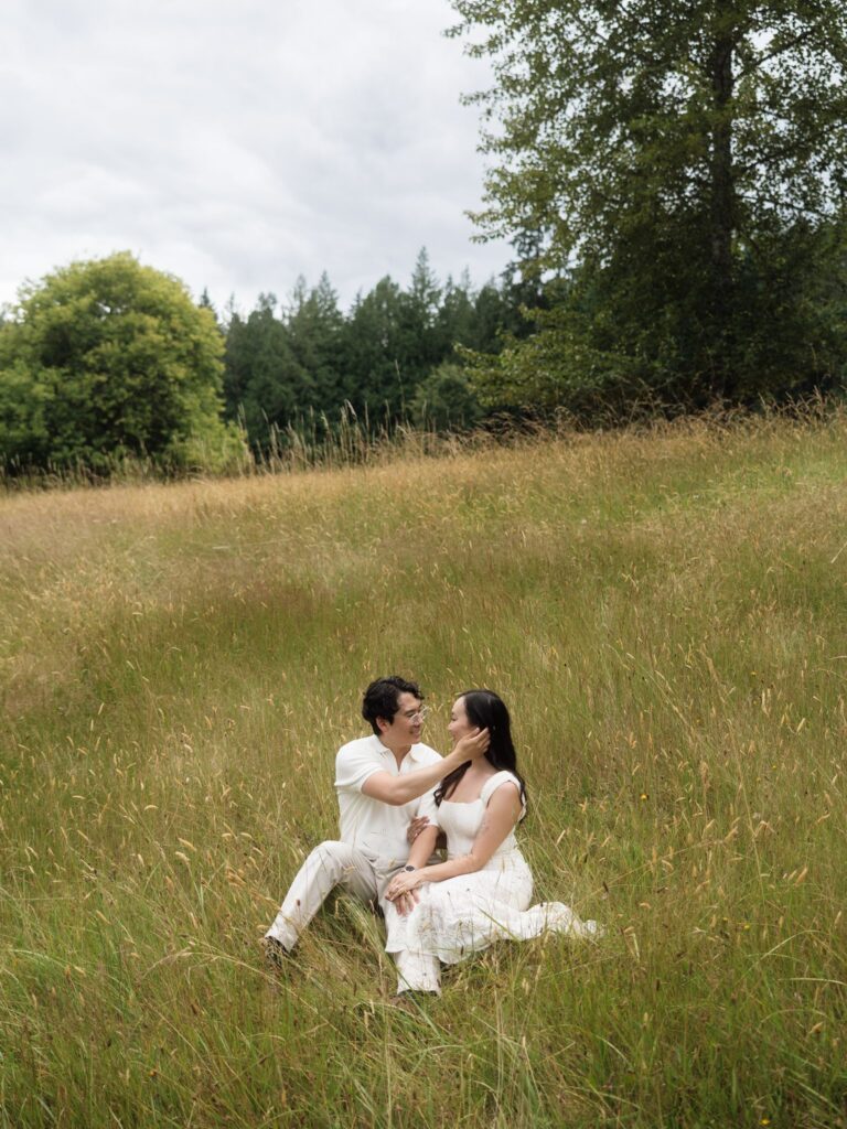 Man tucking his fiancés hair behind her hears during their Bloedel Reserve engagement photos in an open field.