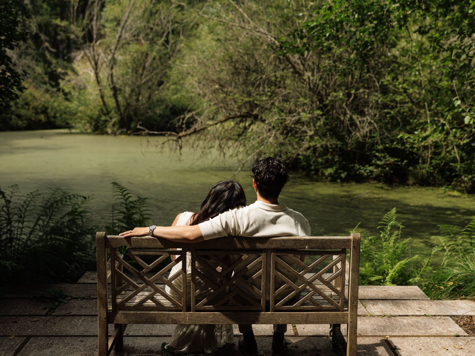 Couple sitting on a bench near the pond at Bloedel Reserve for their romantic engagement photos.