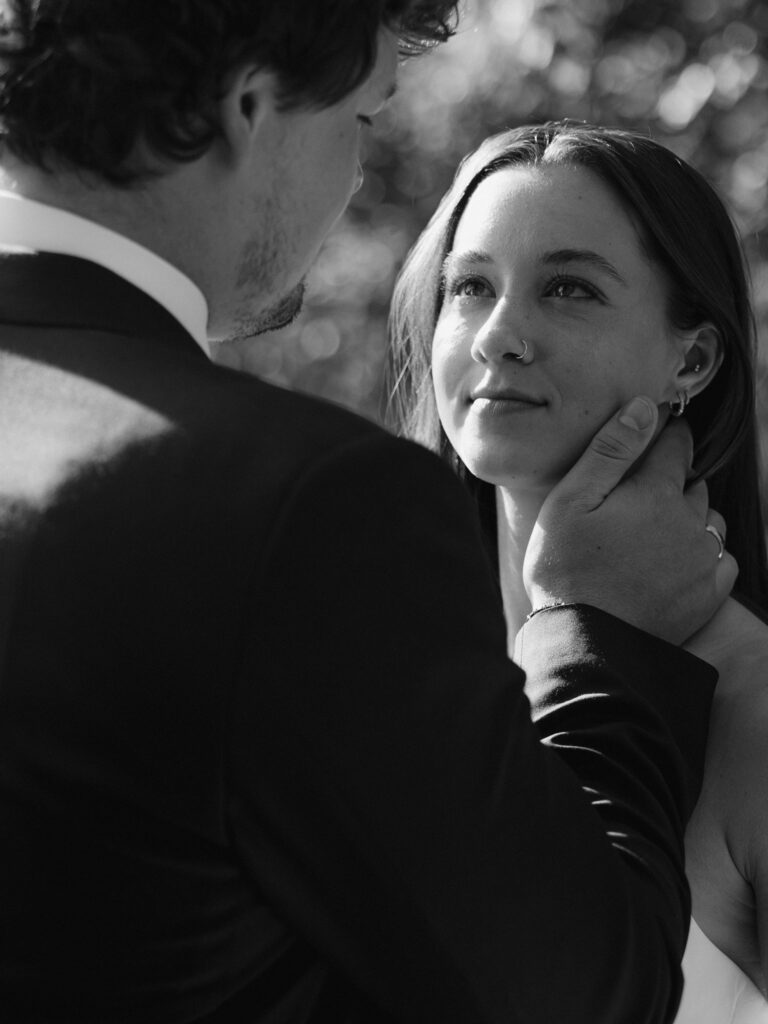 Black-and-white portrait of a groom gently holding the bride’s face.