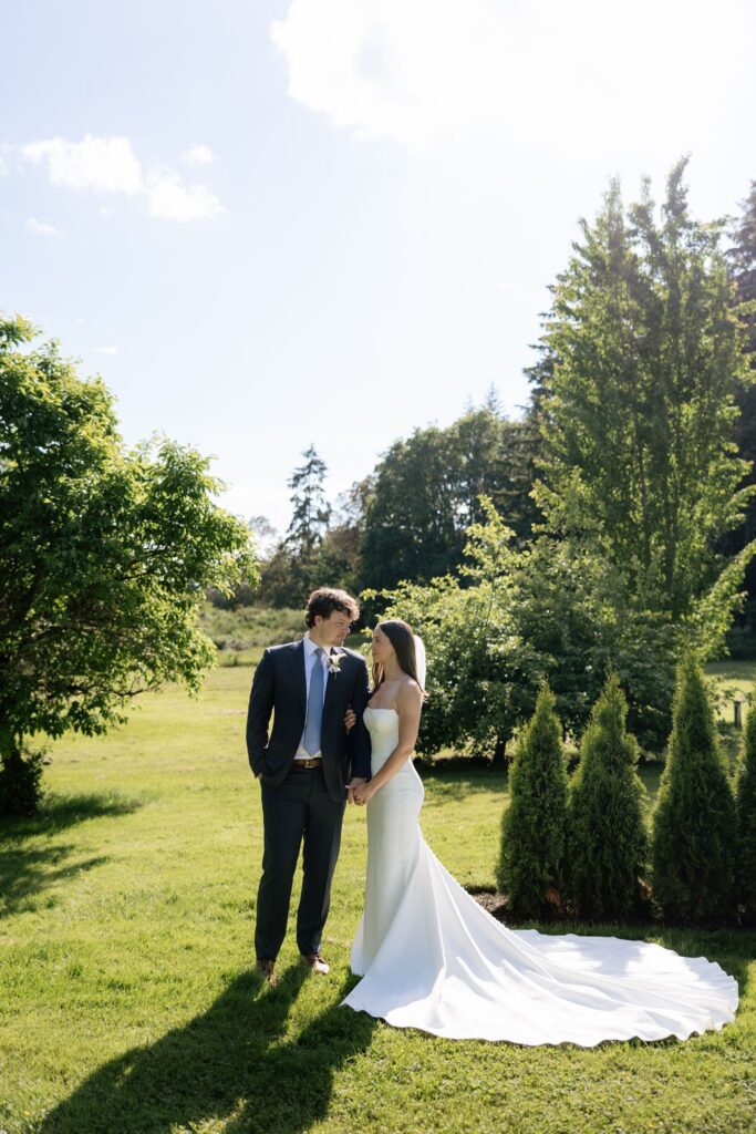 Bride and groom holding hands on an open lawn after their Froggsong Gardens wedding.