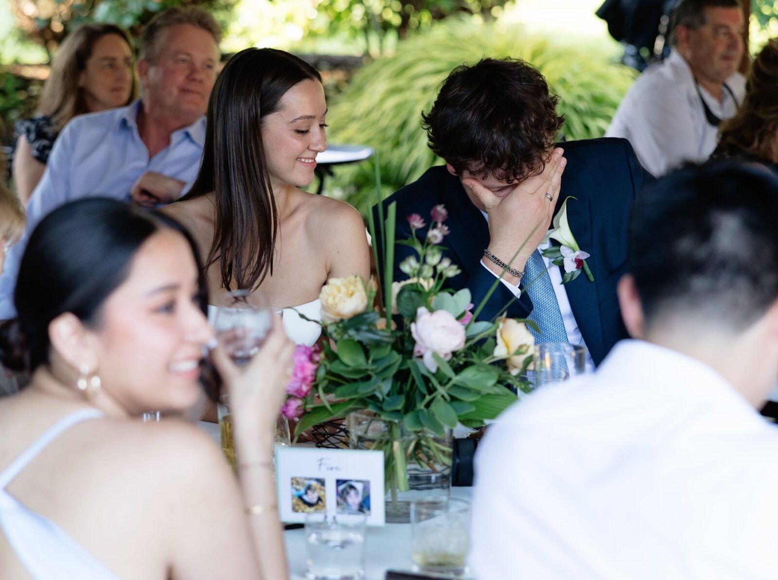 Emotional groom covering his face during a heartfelt wedding reception speech.