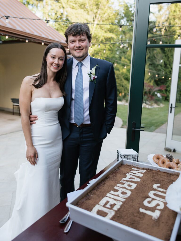 Bride and groom smiling with their wedding cake.