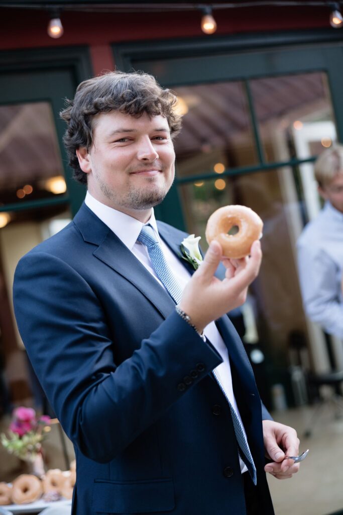 Groom smiling with a donut in hand.