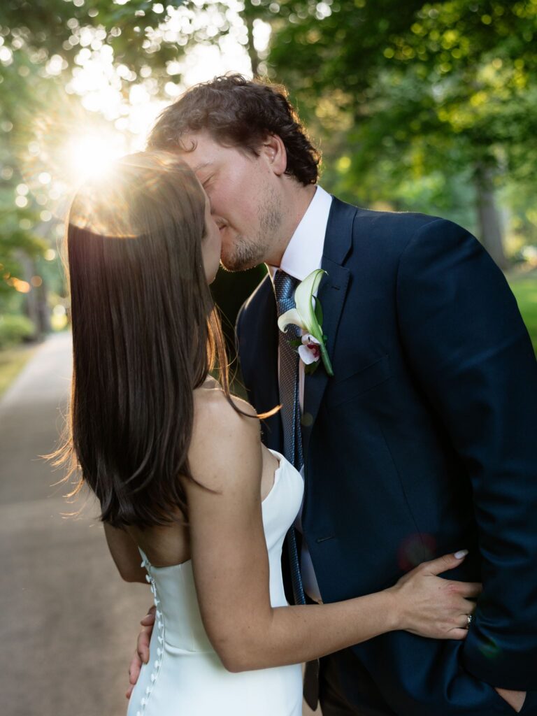Bride and groom kissing during golden hour for their Froggsong Gardens wedding portraits.