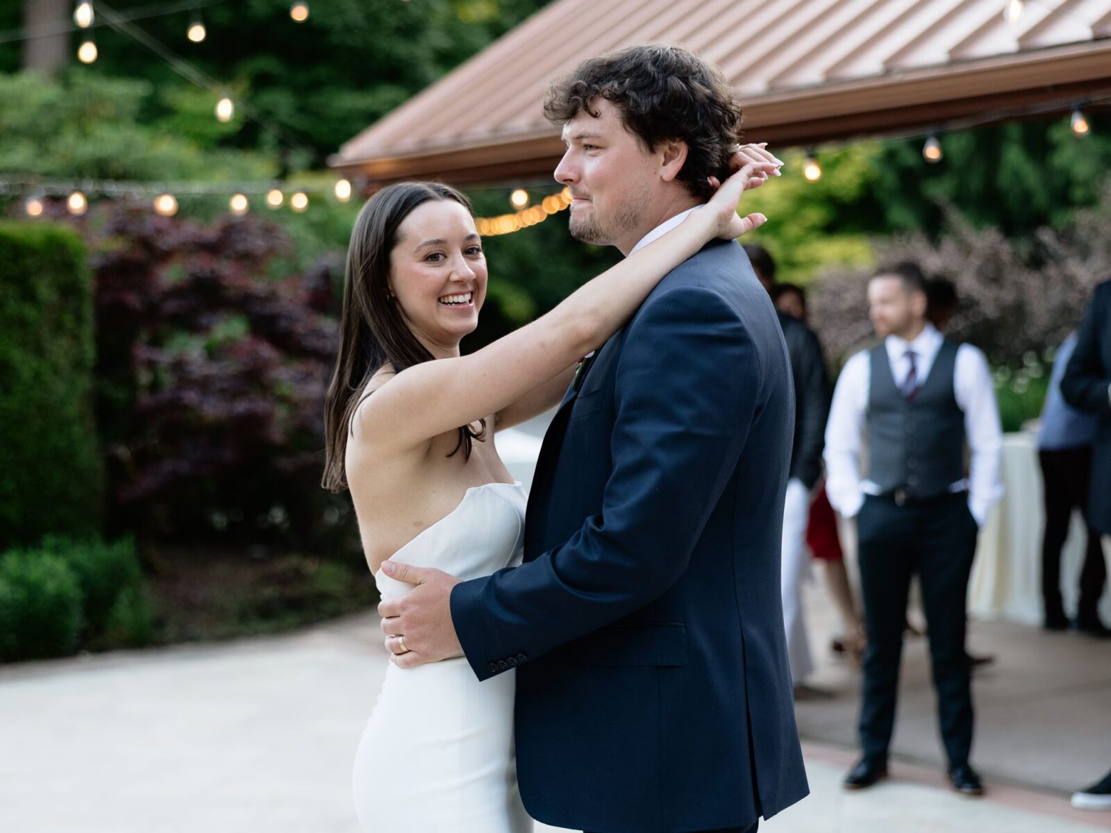 Bride and groom sharing their first dance beneath twinkle lights at the reception.