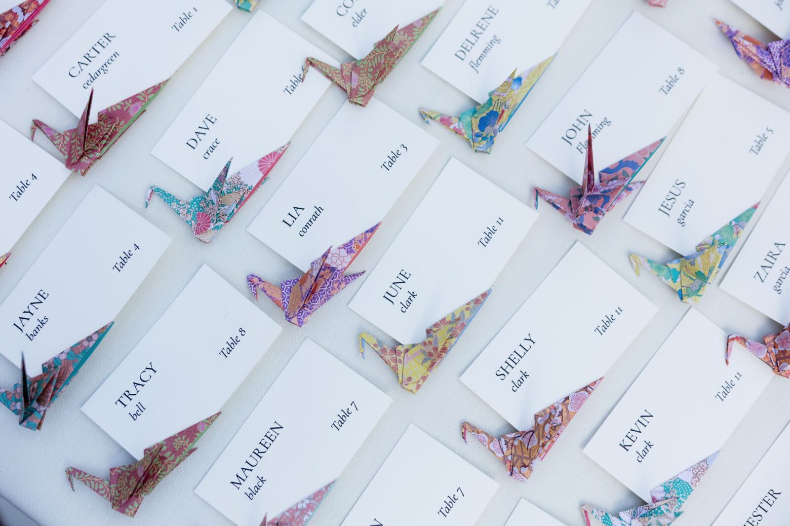 Colorful origami crane place cards displayed for wedding guests.