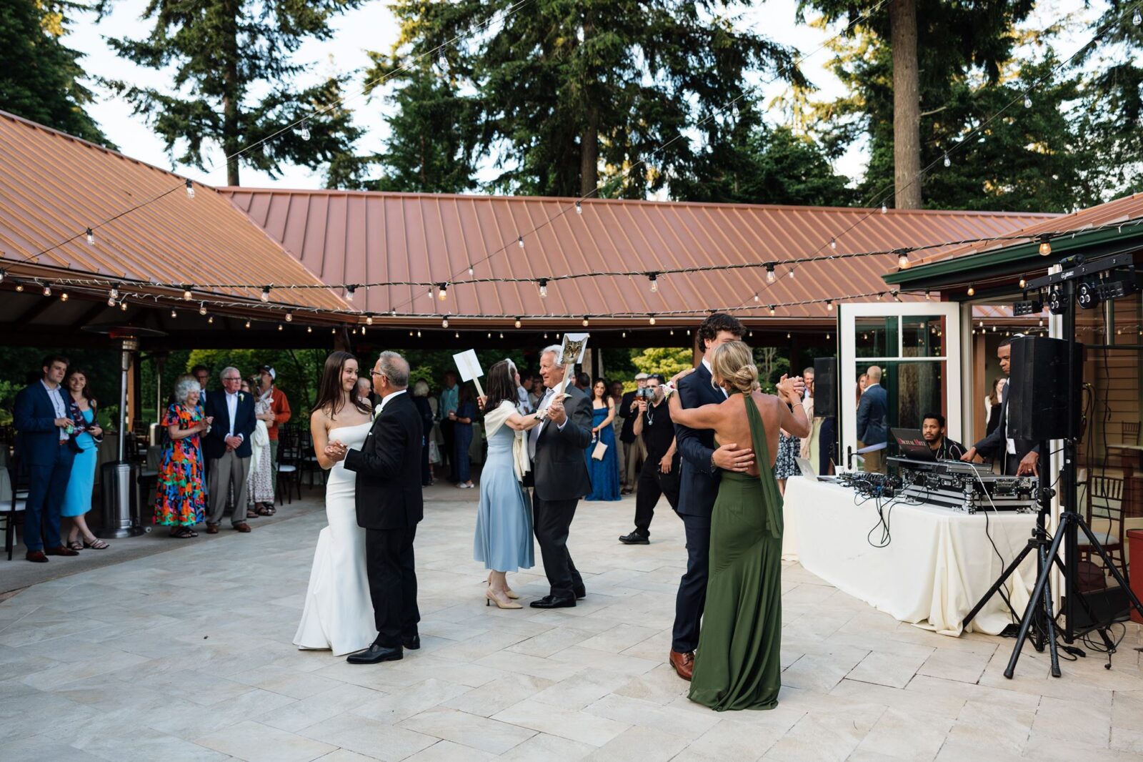 Bride dancing with her father while the groom dances with his mother.