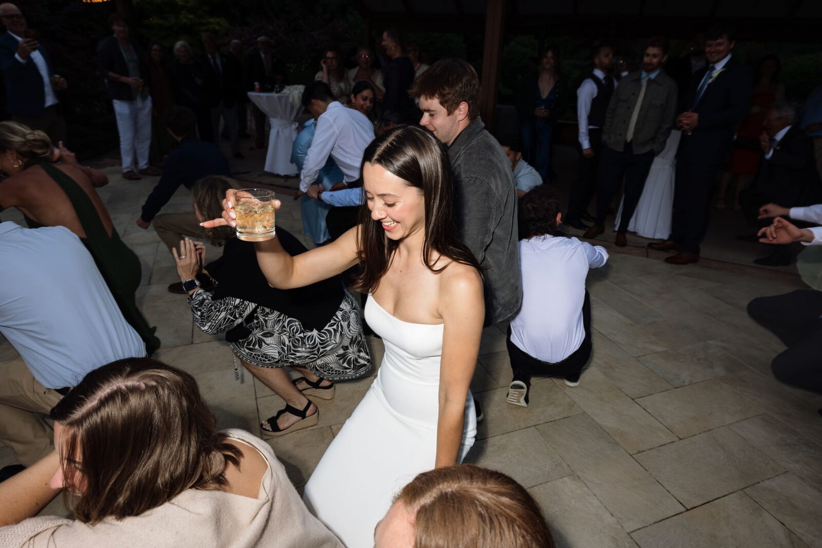 Bride dancing with a drink in hand during her Froggsong Gardens wedding reception.