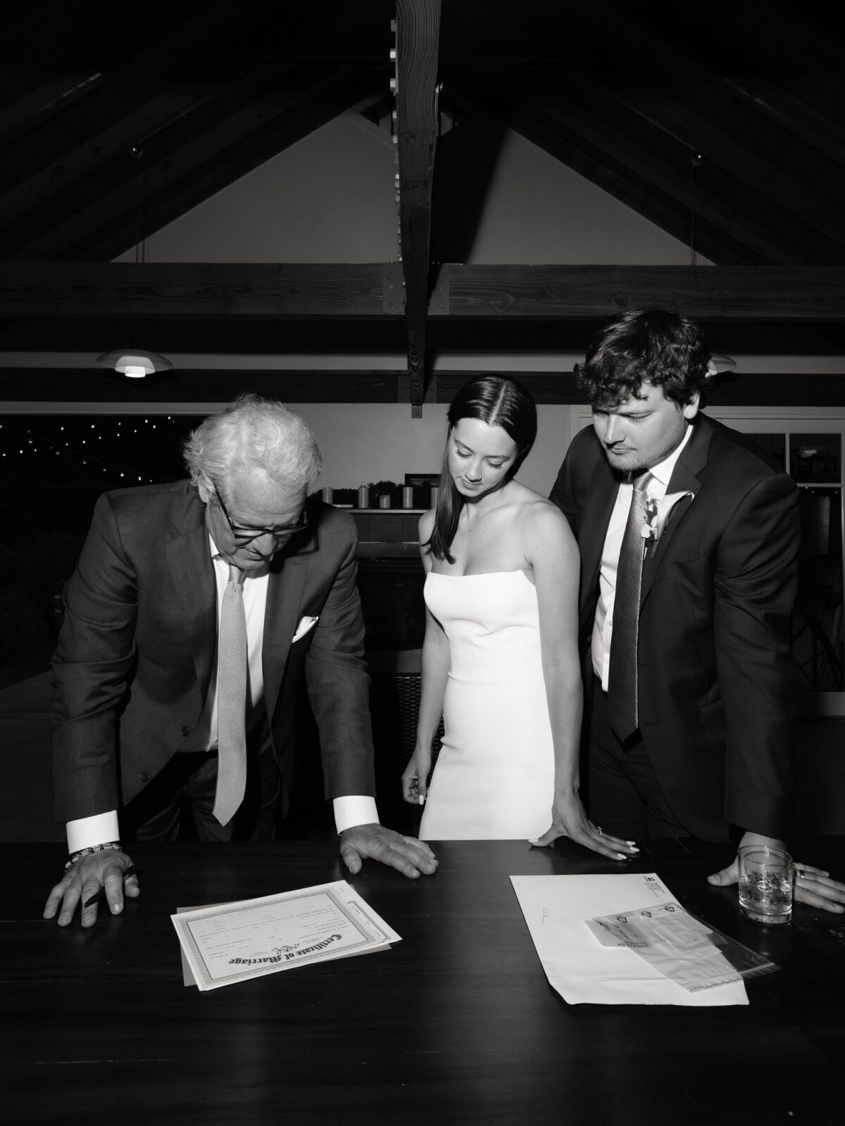 Black and white photo of a bride and groom signing their marriage certificate.