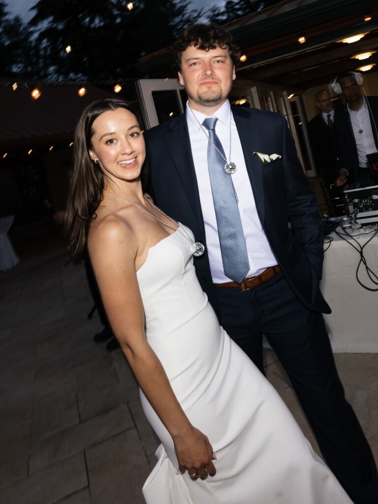 Bride and groom smiling for a flash photo during the reception.
