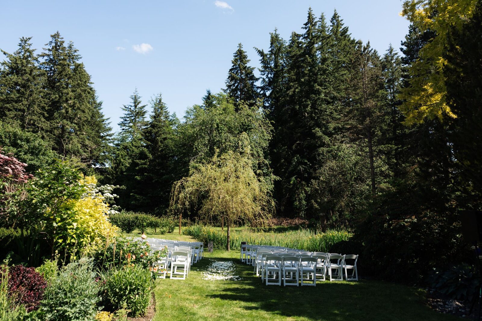 Wide view shot of an outdoor wedding ceremony set up at Froggsong Gardens in Vashon Island, WA.