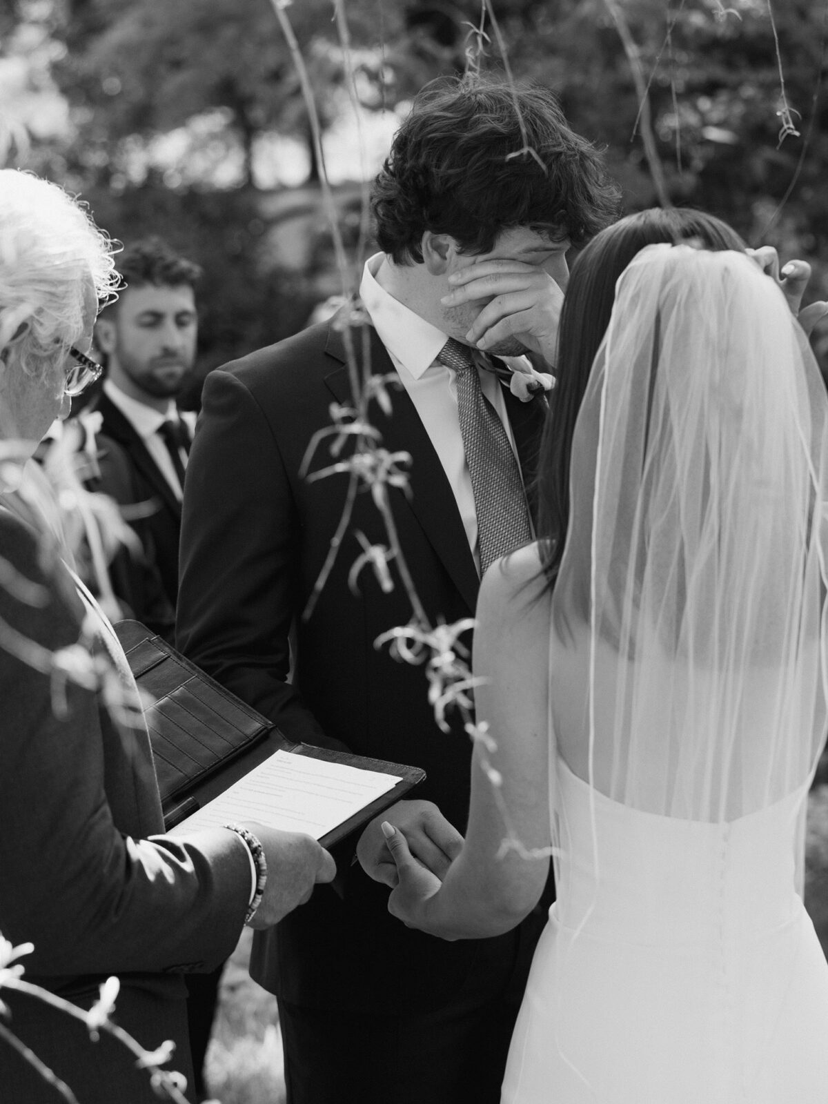 Black-and-white photo of an emotional groom during the wedding ceremony.