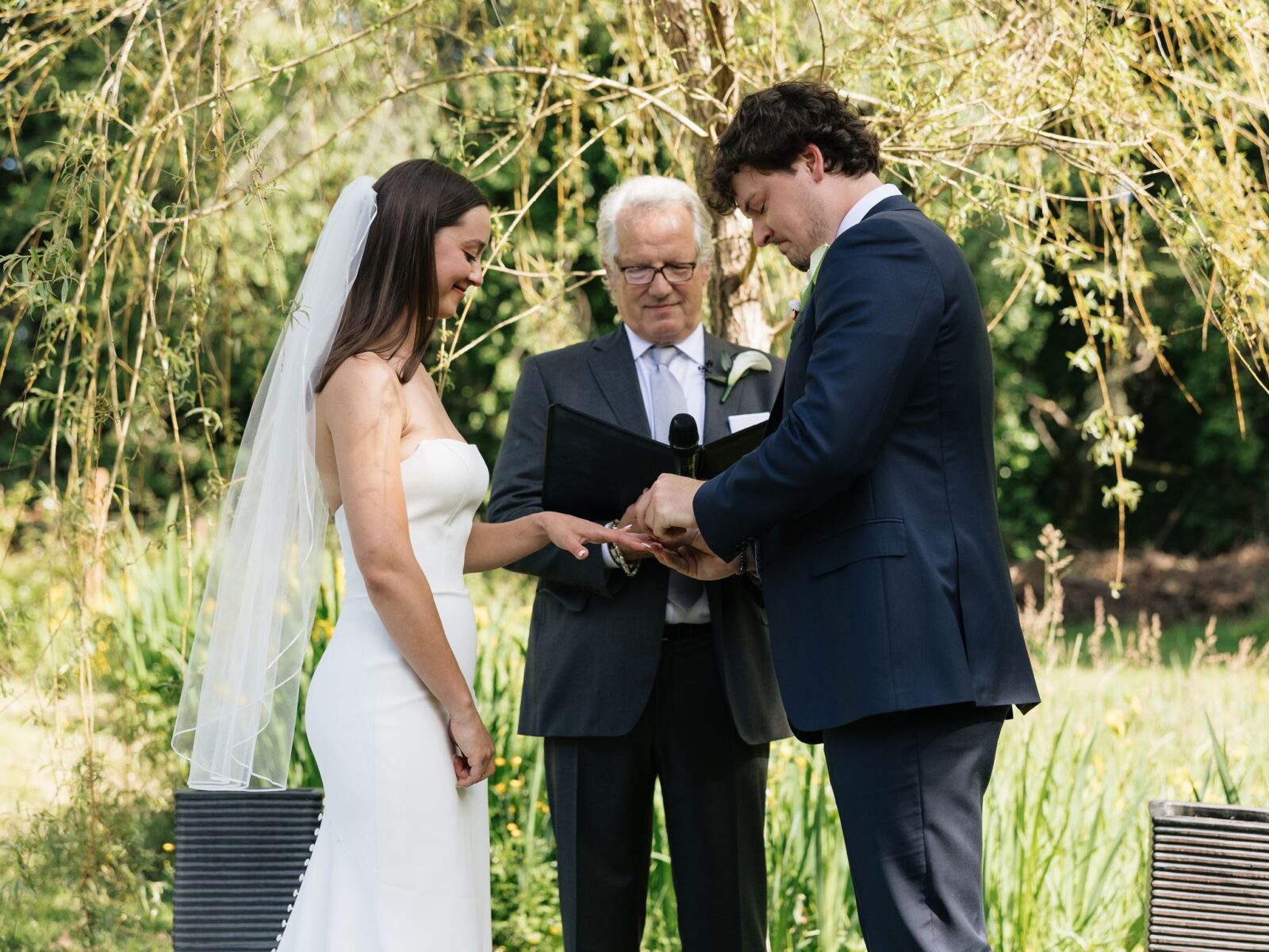 Groom placing a wedding ring on the bride’s hand during the ceremony.