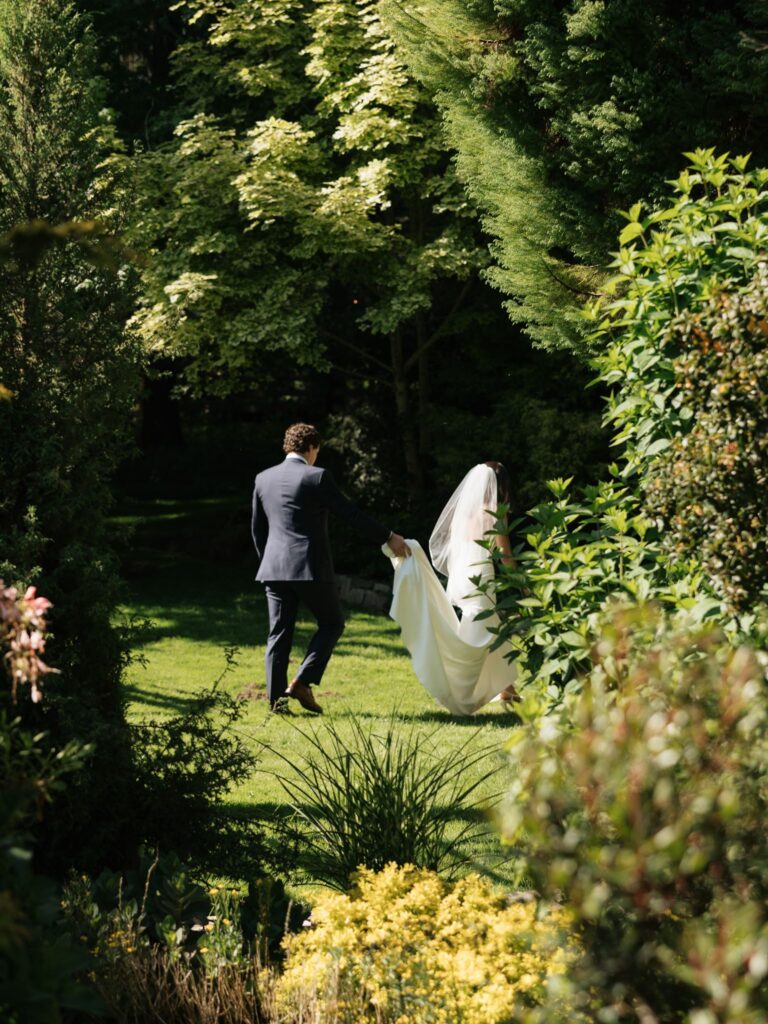 Bride and groom walking through the gardens together after their ceremony.
