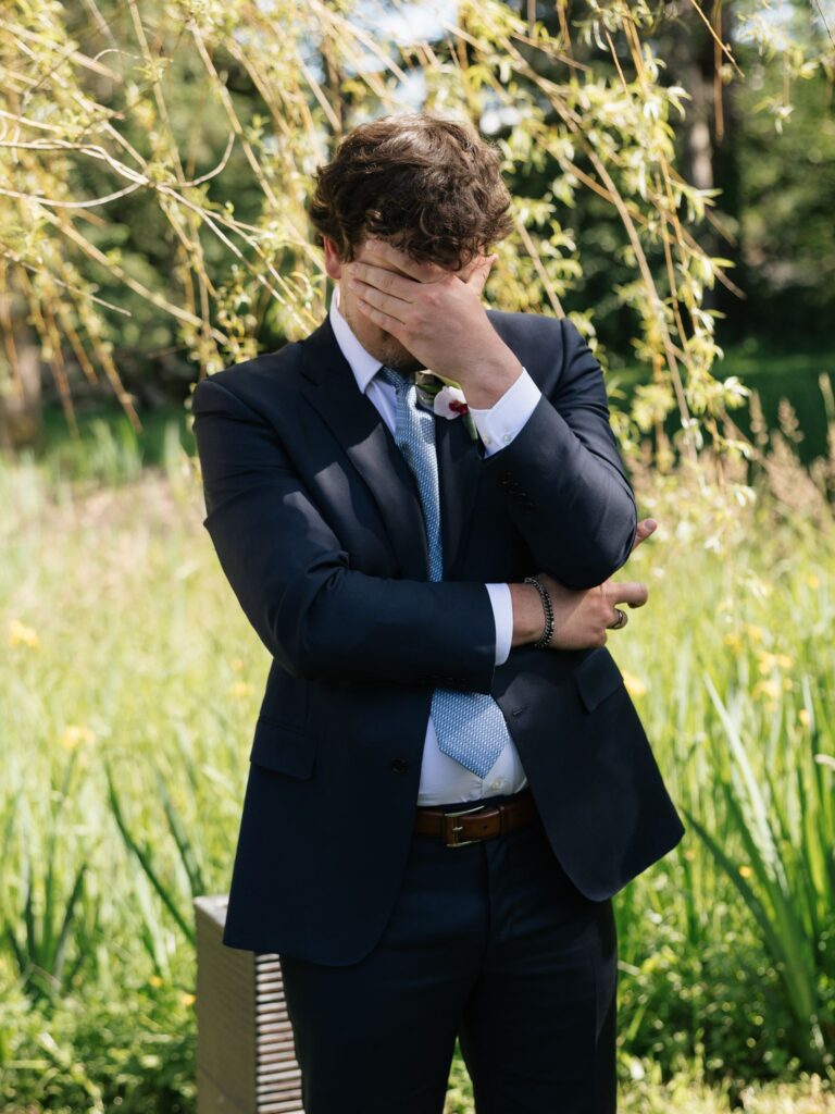 Groom wiping away tears before an outdoor ceremony at Froggsong Gardens.