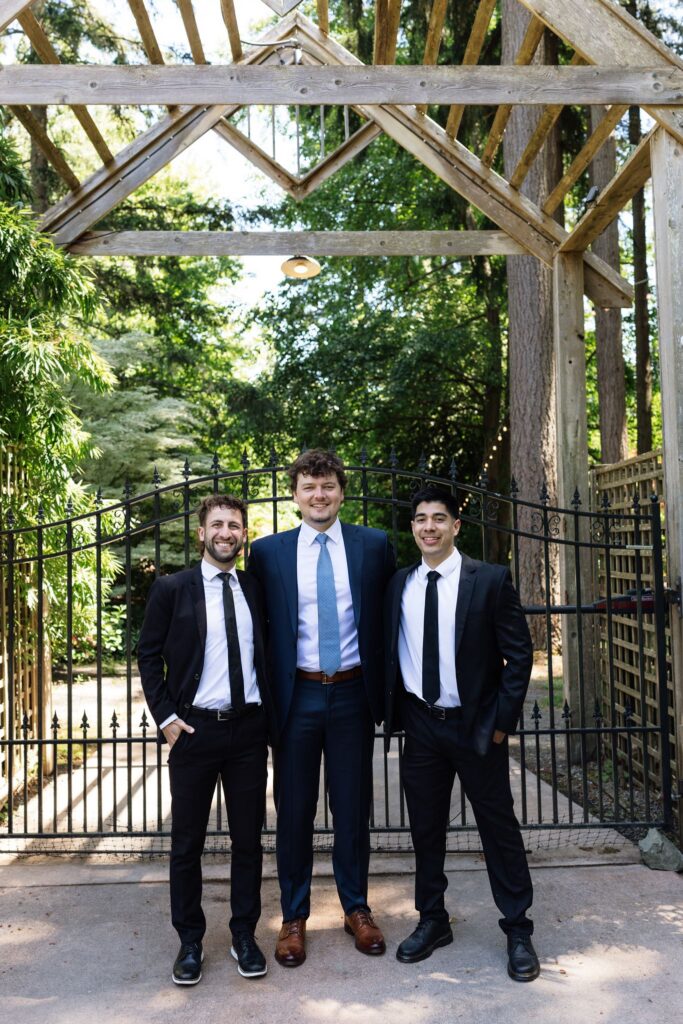 Groom and groomsmen posing in front of the garden entrance gates.
