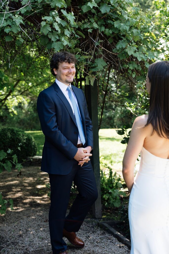 Groom smiling at the bride during their garden first look.