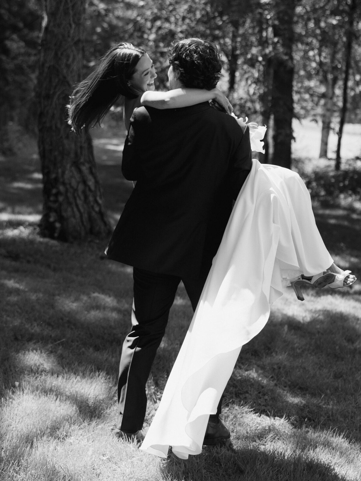 Groom carrying the bride during candid wedding portraits in the gardens.
