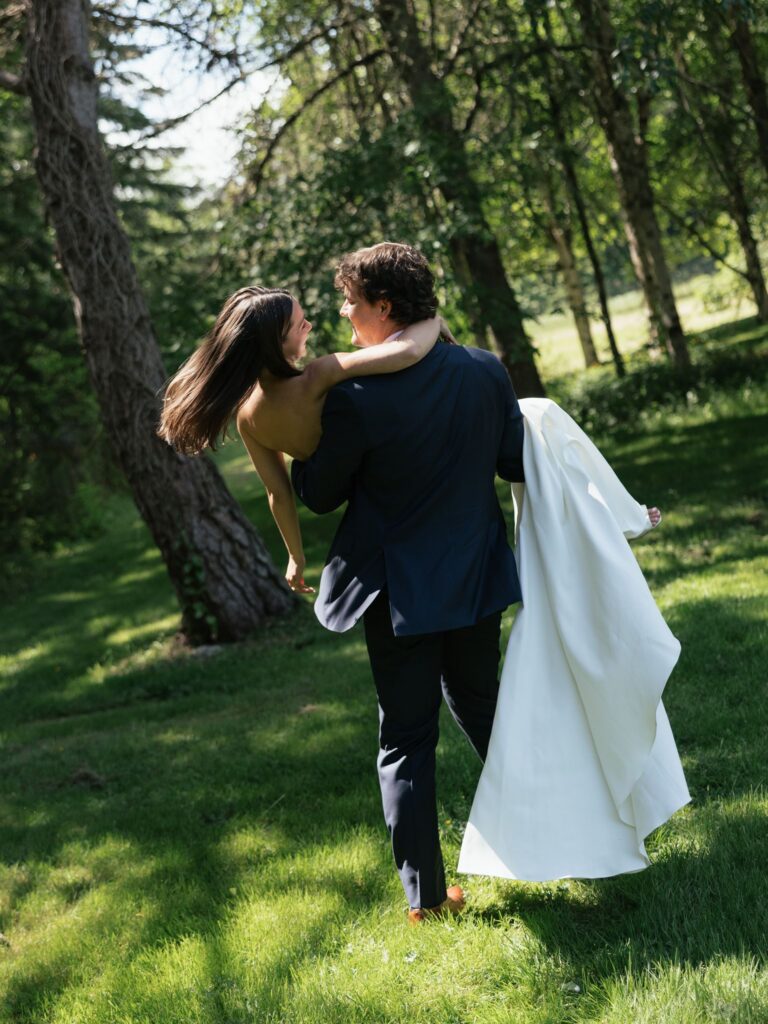 Groom carrying the bride during candid wedding portraits in the gardens.