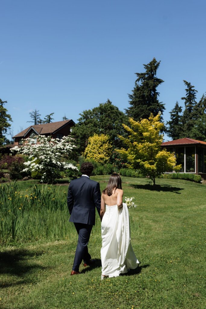 Bride and groom walking across the lawn at Froggsong Gardens.