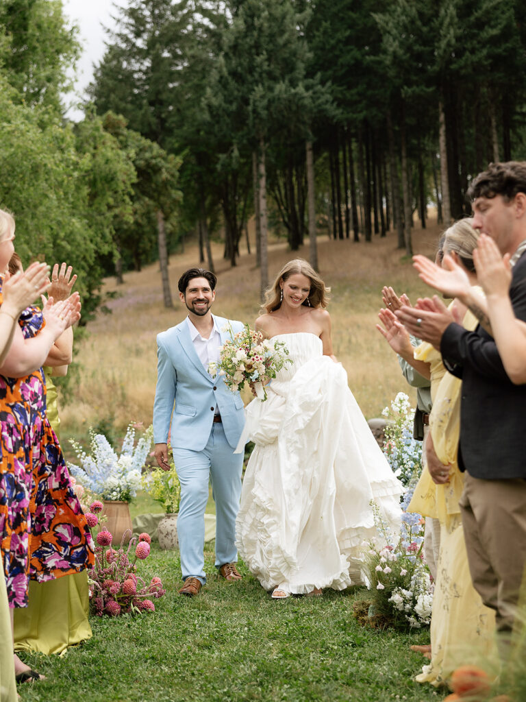 Bride and groom walking back down the aisle as husband and wife after their Maysara Winery wedding ceremony outdoors.