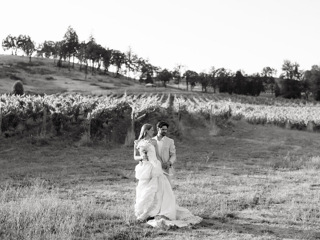 Black and white wide shot of a bride and groom posing in the vineyards at Maysara Winery.