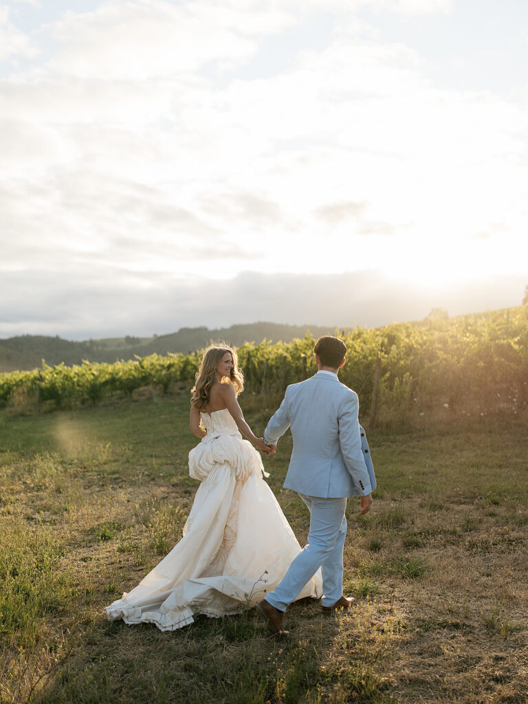 Golden hour wedding photo of a bride and groom walking the vineyards during golden hour at Maysara Winery.