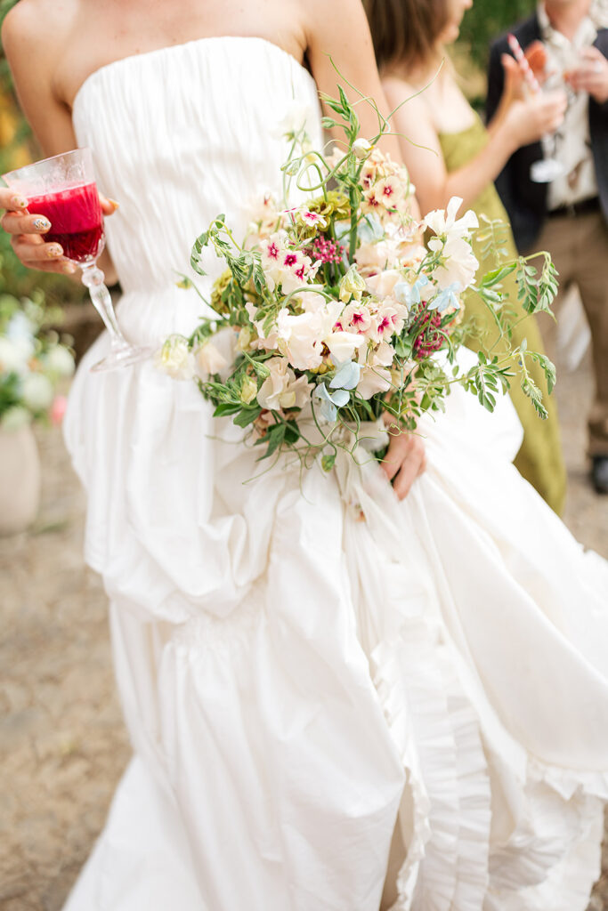 Bride holding a glass of wine and posing for a photo.