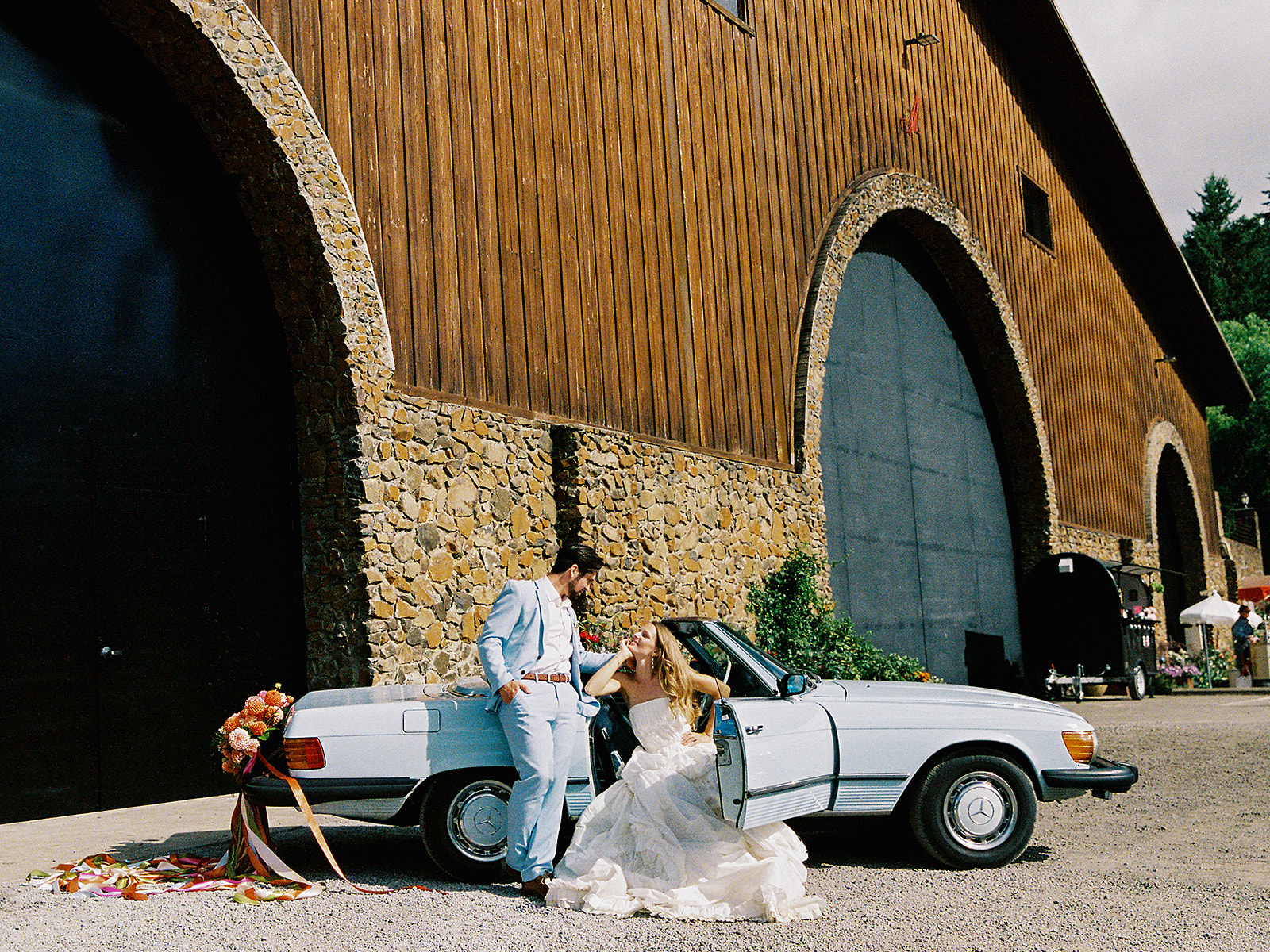 Bride and groom posing with a vintage blue car outside of Maysara Winery in Oregon.