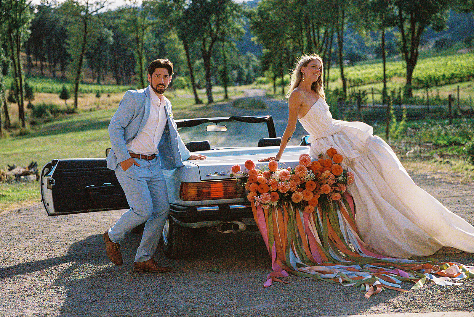 Bride and groom posing with a vintage blue car outside of Maysara Winery.