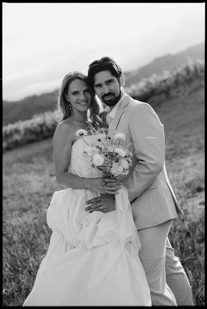 Blac and white photo of the bride and groom posing outdoors.