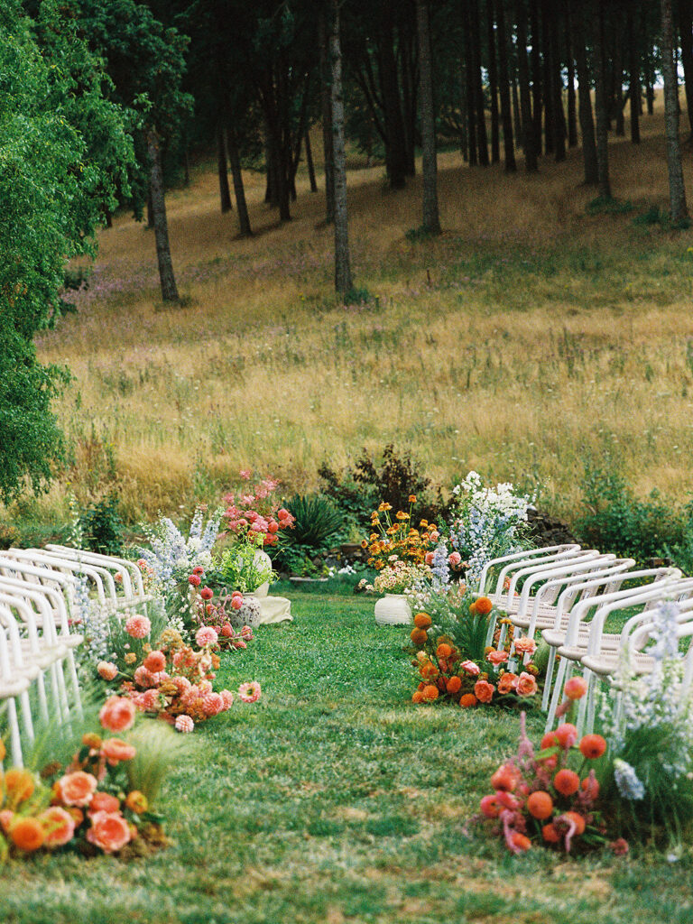 Outdoor wedding ceremony on the lawn at Maysara Winery with colorful florals and a couple standing at the altar captured on film.