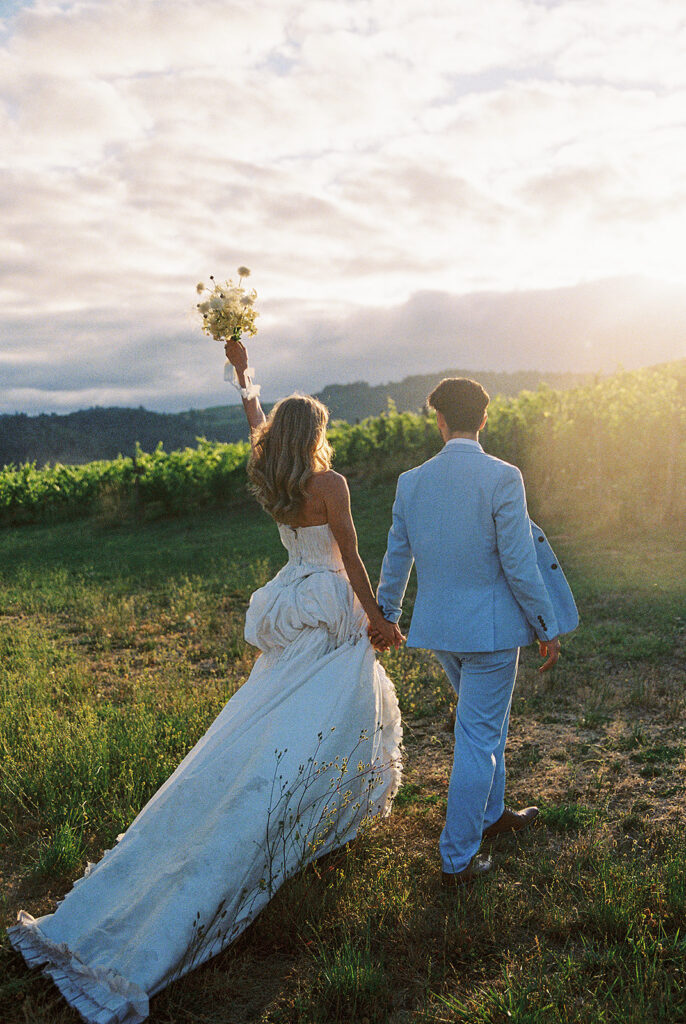 Bride and groom walking into the vineyards during golden hour for their Maysara Winery wedding photos.