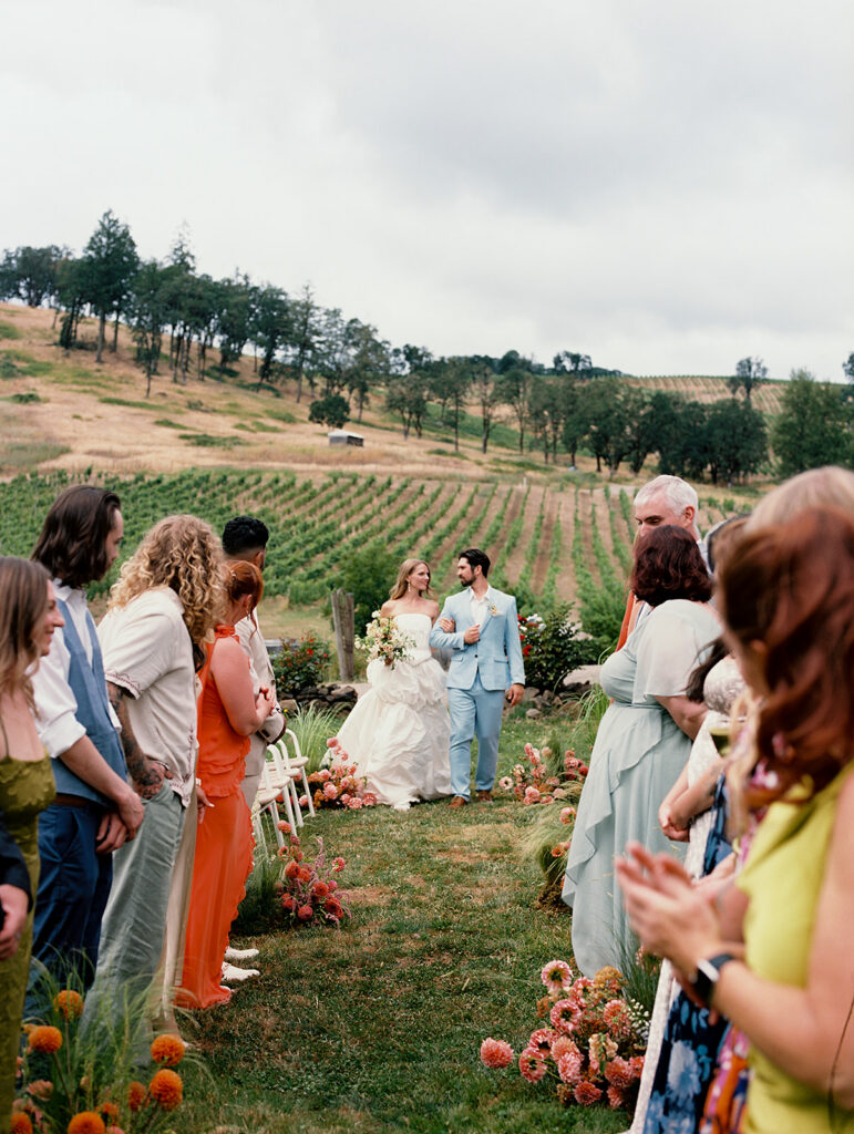 Bride and groom walking down the aisle together for their Maysara Winery wedding ceremony outdoors.