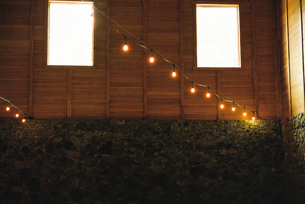 Interior shot of the winery at Maysra Winery with wood paneled and stone walls and string lights overhead.