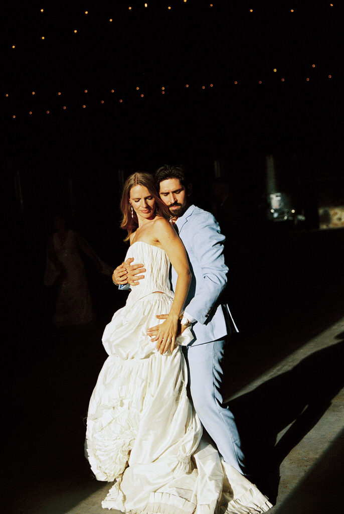 Couple dancing during a wedding reception inside Maysara Winery, with the bride in a white gown and groom in a light blue suit.