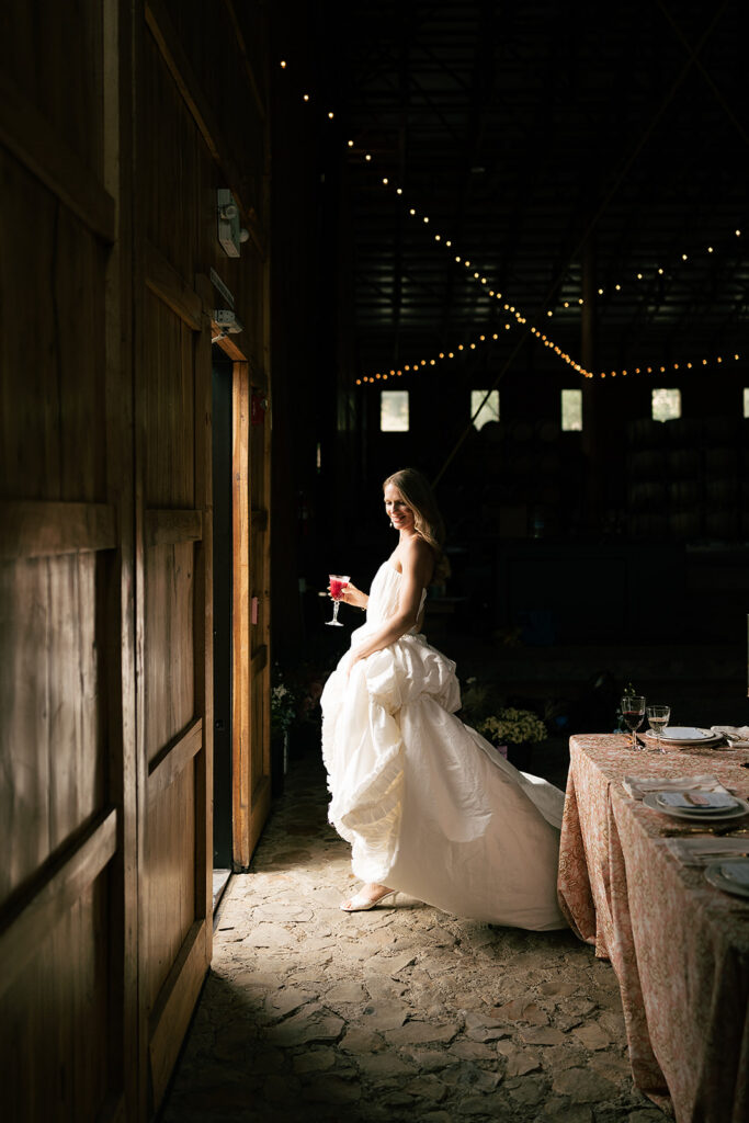 Bride holding a glass of champagne in the doorway of the winery at Maysra Winery in Oregon.