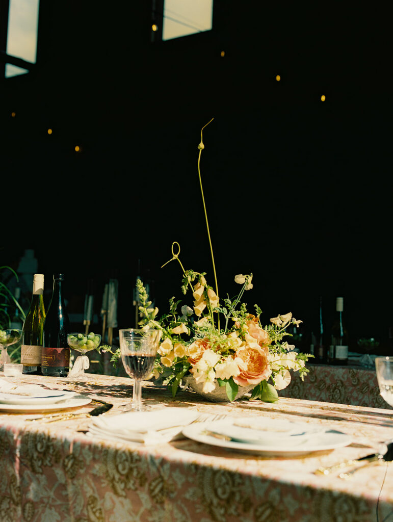 Wedding reception table at Maysara Winery with patterned linens, peach florals, glassware, and place settings.