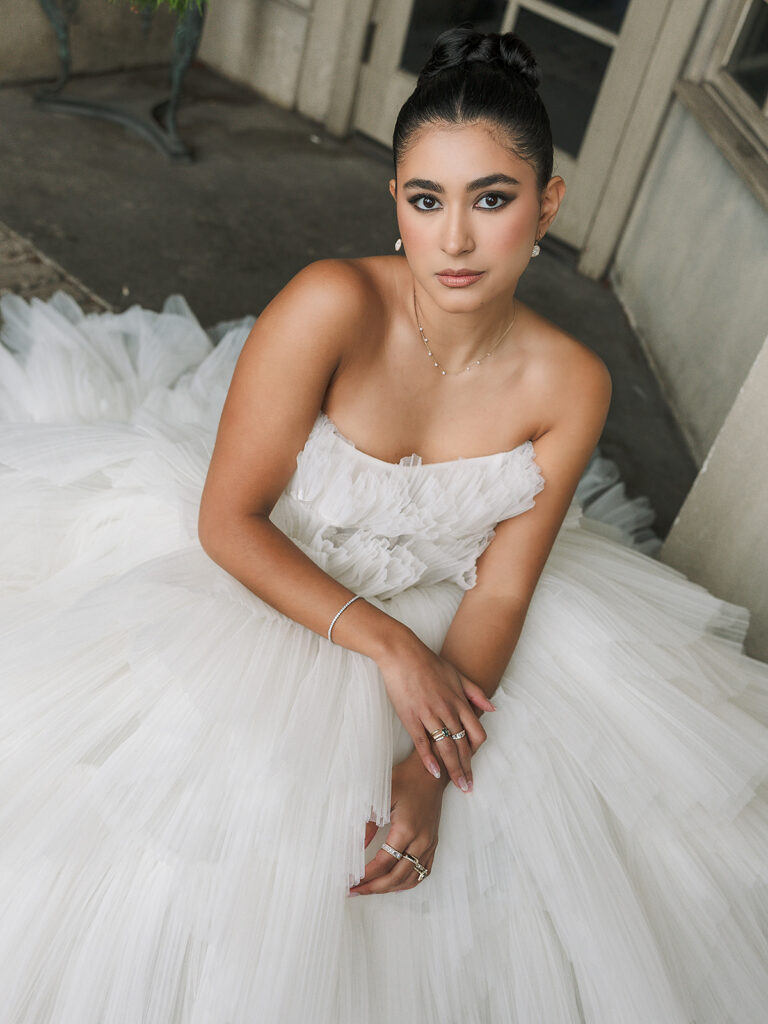 Bride posed in a voluminous white tulle gown with delicate jewelry.