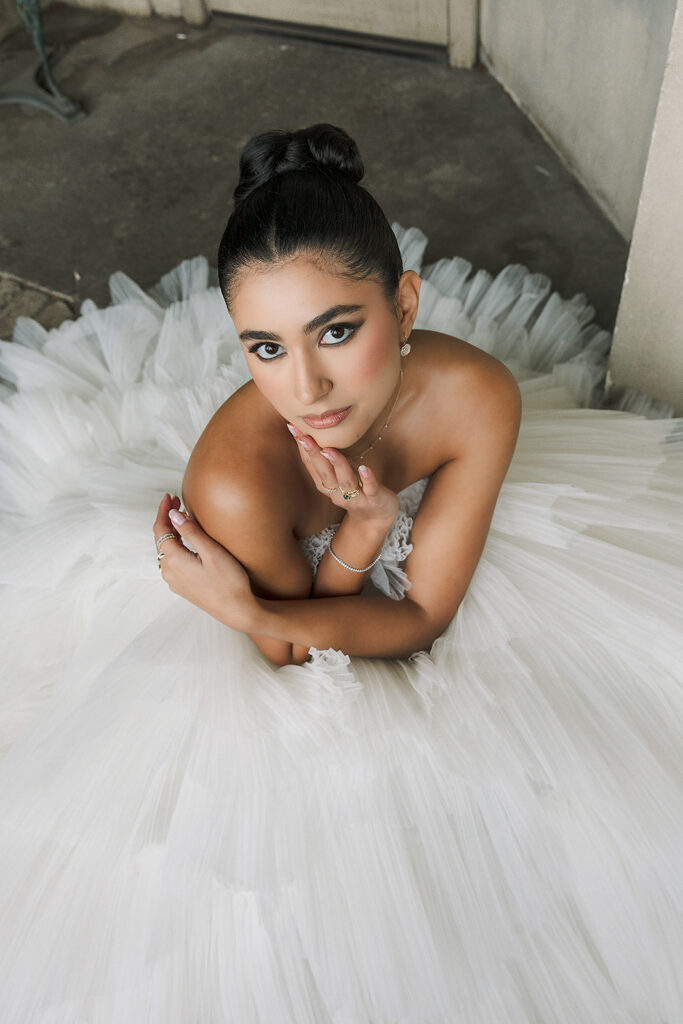 Bride posed in a voluminous white tulle gown with delicate jewelry.