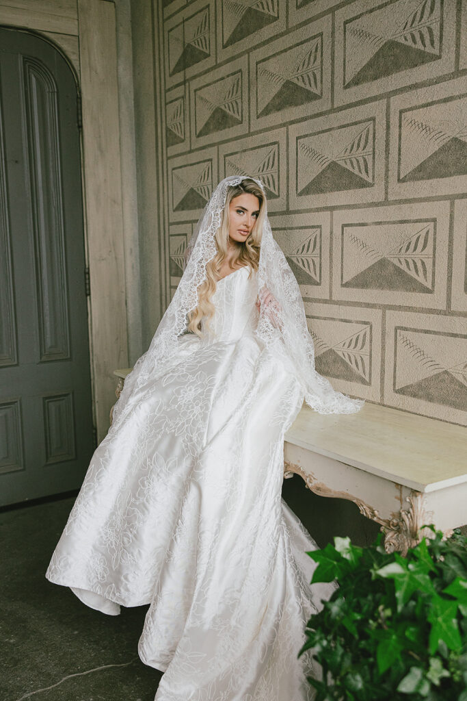 Bride sitting on a bench in front of a textured wall inside The Ruins wedding venue in Seattle, Washington.