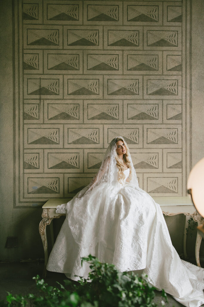 Bride sitting on a bench in front of a textured wall inside The Ruins wedding venue in Seattle, Washington.