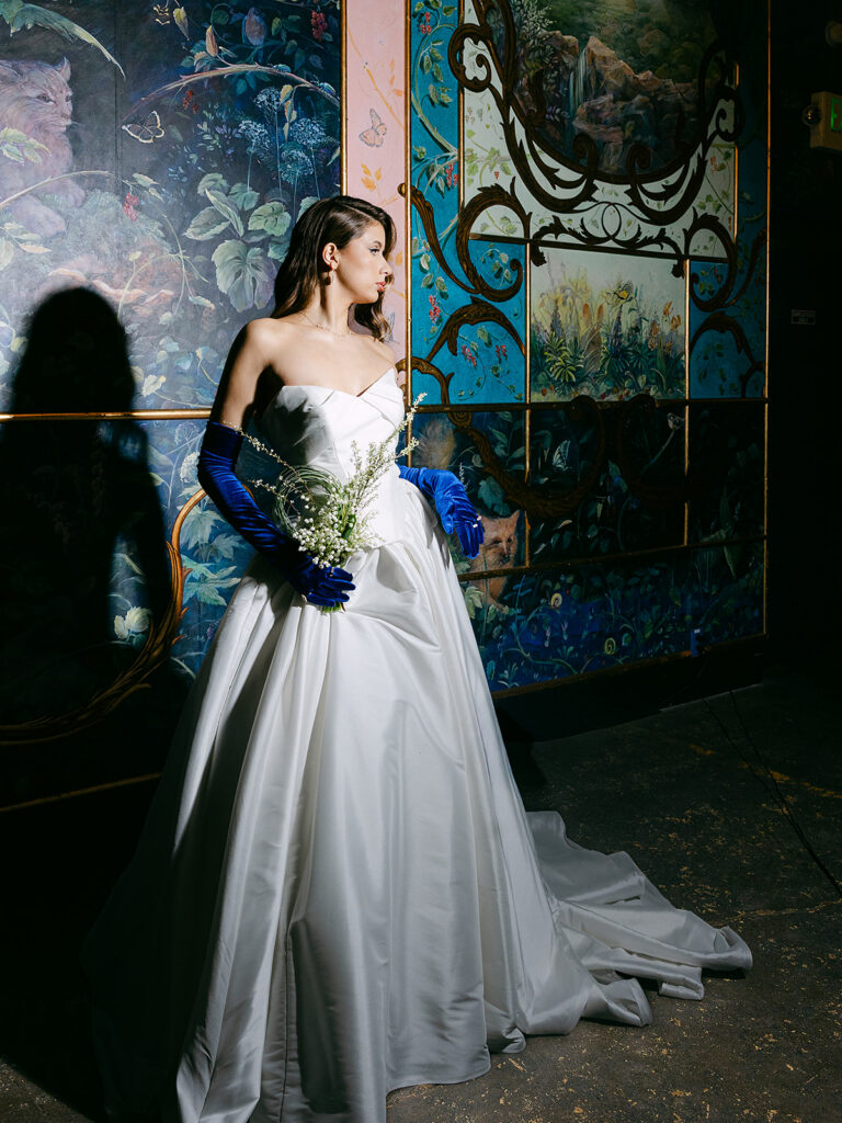 Bride posing in front of a blue painted wall inside The Ruins in Seattle for a wedding editorial.