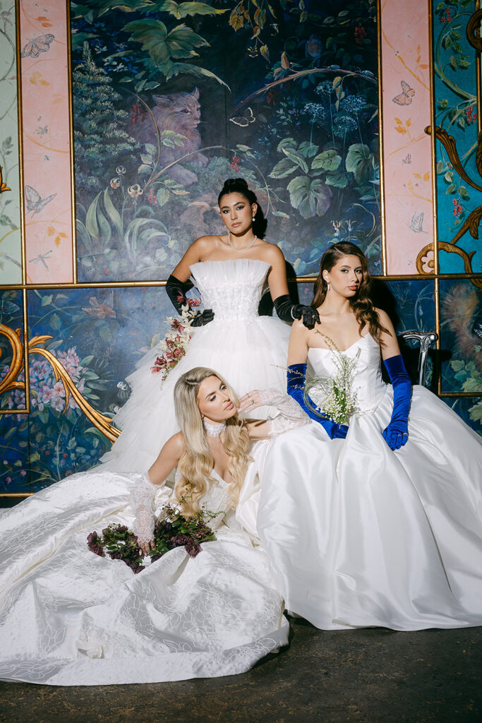 Three brides posing in front of a colorful mural inside The Ruins in Seattle for a wedding editorial.