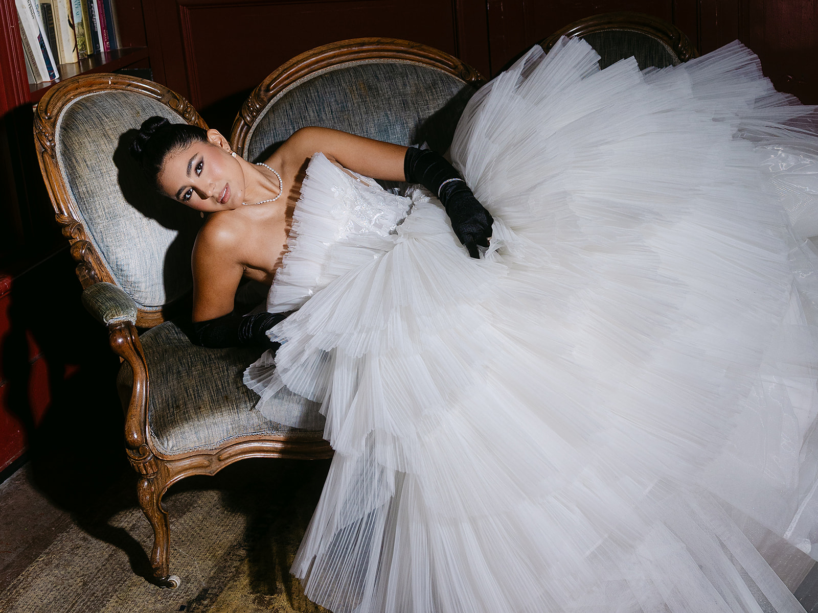 Wide flash shot of a bride laying across a vintage blue couch inside The Ruins in Seattle for a wedding editorial.