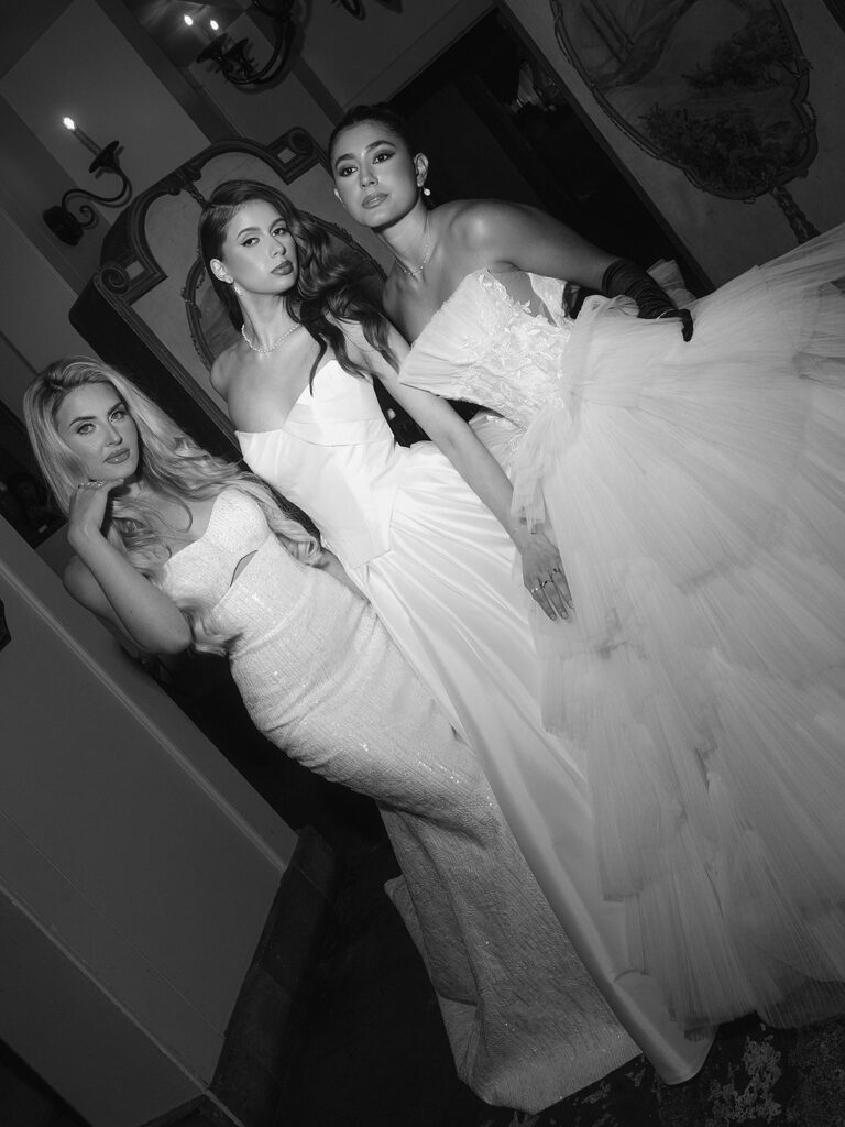 Black and white flash photo of three brides posing together for a fashion editorial.